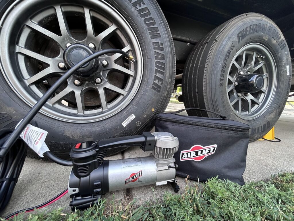 Portable air compressor connected to RV travel trailer tire.