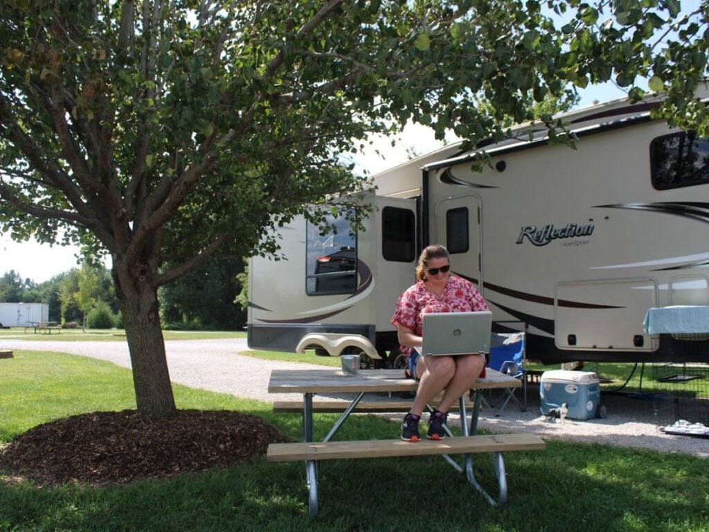 Woman with laptop sitting on RV campsite picnic table