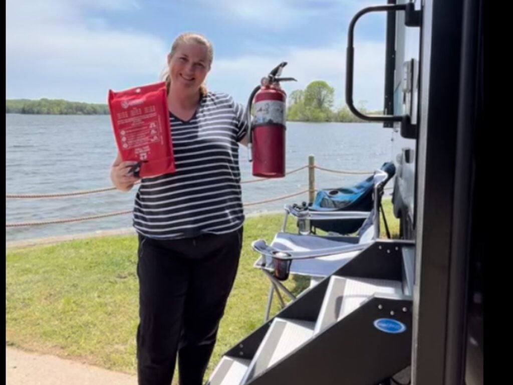 Woman at RV campsite holding fire extinguisher and fire blanket