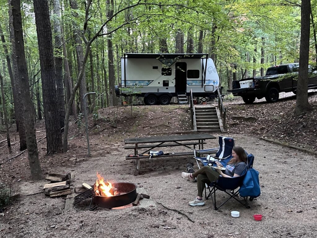 Woman eating breakfast by campfire