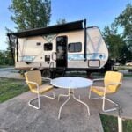 Travel trailer RV at campsite with yellow chairs