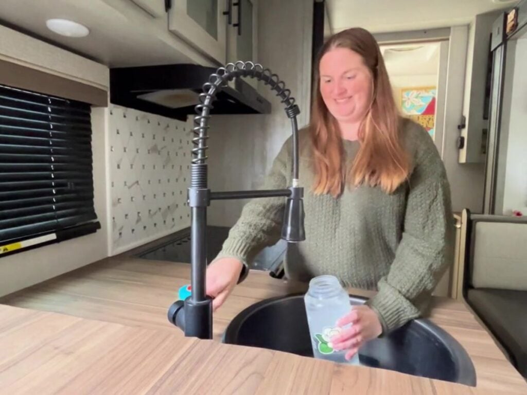 Woman filling water bottle in RV sink